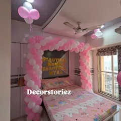 A sweet and simple bedroom decoration to welcome a new baby or for a birthday. This setup features a pink and white balloon arch over the bed, creating a lovely frame.