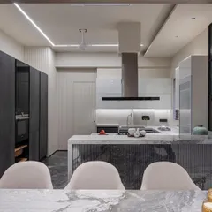 This shot from the dining area shows how the kitchen's design is integrated with the rest of the home. The fluted stone on the island front adds texture and connects with the sophisticated materials used in the living space.