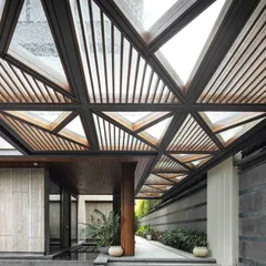 The entrance to the Bammi Residence is designed as a dramatic transition from the urban exterior to a serene interior. The geometric, slatted canopy filters natural light, creating dynamic patterns of light and shadow on the steps and water body below. This architectural feature sets a tone of thoughtful design and a deep connection to natural elements, which is a hallmark of our work.