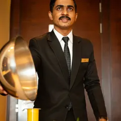 A photograph capturing the warm hospitality and excellent service at Courtyard by Marriott. This image was created to highlight the in-room dining experience for their marketing materials.