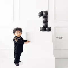 Standing tall for his first birthday portrait. This minimalist setup with clean white lines and a modern balloon number puts all the focus on the birthday boy.