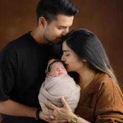 The complete family. A father’s gentle kiss on the mother’s forehead while she holds their newborn creates a portrait filled with love, protection, and tenderness.