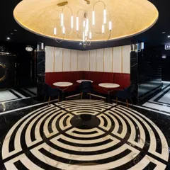 A striking feature in the INOX Jalosa lobby is this circular seating area, defined by a dramatic labyrinth-style floor inlay. The design creates a natural gathering point and a strong visual anchor in the space, complemented by a modern chandelier that casts a warm glow.