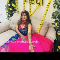 A beautiful bride at her mehendi ceremony, showing off the intricate henna art that extends up her forearms.