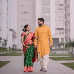 A full-length shot of the couple walking together during their maternity session. The modern building in the background gives it a contemporary urban feel.