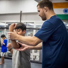 Personal attention makes all the difference. A coach fine-tunes a student's arm position, ensuring they not only learn the move but understand the mechanics behind it for effective self-defense.