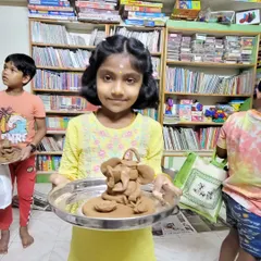 A young girl proudly displays the Ganesha idol she crafted herself. These workshops are not just about art; they are about creating lasting memories and celebrating traditions together.