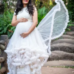 A beautiful white gown with a ruffled, cloud-like skirt. The fabric creates a soft, dreamy texture, perfect for a fairytale maternity shoot.