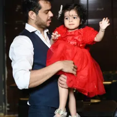 A father holds his young daughter, capturing a natural and loving interaction between them.
