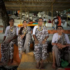 A group of four Koli women from Edvan, Saphale, dressed in their traditional printed sarees and gold jewelry, sitting together with grace and strength.