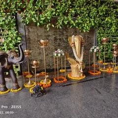 A sacred corner featuring a Ganesha idol, adorned with floral garlands and surrounded by traditional brass lamps and flower arrangements to welcome guests with blessings.
