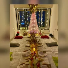 An intimate and cozy floor seating arrangement perfect for a bridal shower or special dinner. The decor features a warm, candlelit tablescape, dried wheat centerpieces, and a beautiful canopy of fairy lights, creating a magical and inviting atmosphere.