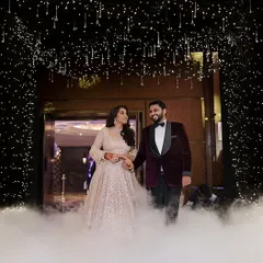 A grand entrance for a Sangeet night, with the couple walking through a cloud of low fog under a ceiling of twinkling star-like lights. This creates a dreamy, "written in the stars" moment.