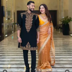 The complete look. Our black sherwani with detailed gold threadwork on the collar, placket, and cuffs, paired with tailored trousers for a sharp, regal silhouette.