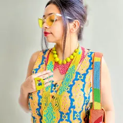 This look is all about dopamine dressing with accessories. I've layered colorful beaded necklaces, a fabric hair accessory, and a multi-color bag over a printed dress to create a joyful, hippie-chic vibe. More is more!