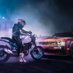 Our performances are a carefully choreographed dance between cars and bikes. This shot captures a moment of synergy between a stunt rider and a drifting muscle car, a highlight of our live event packages.