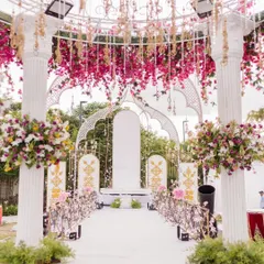The view looking down the aisle through the floral archway. The path is lined with flowers, leading to a beautifully decorated stage, creating a grand sense of arrival.