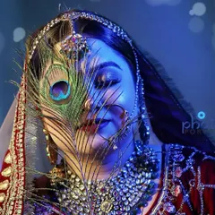 An artistic bridal portrait using a peacock feather. This creative shot with dramatic blue lighting is perfect for a bride who wants something unique and memorable.