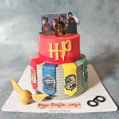 "Happiness can be found, even in the darkest of times." A 10-inch tall, two-tier Harry Potter cake, featuring the four house banners, a golden snitch, and Harry's glasses, all made from fondant.