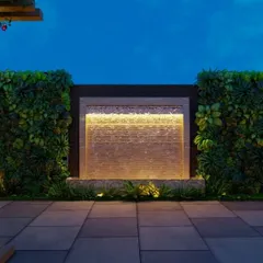 A render of a terrace designed for evening ambiance, featuring vertical green walls flanking a backlit water feature. The combination of soft lighting, stone textures, and lush foliage creates a deeply tranquil environment.