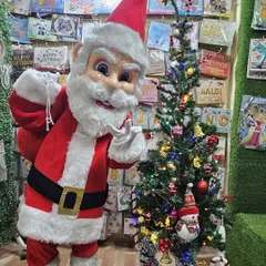 The Santa mascot ready with his sack of gifts next to a Christmas tree. This character is available for hire for Christmas parties, New Year events, and mall promotions.