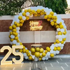 A bright and cheerful 25th-anniversary celebration. This outdoor setup features a yellow and white balloon ring, a neon sign, and large marquee numbers.