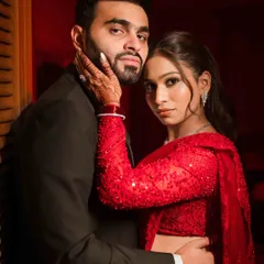 A bold and stylish portrait with dramatic red lighting. The couple's intense gaze and close embrace create a powerful, fashion-forward image perfect for a cocktail party or reception.