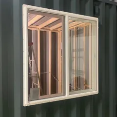 A glimpse into the construction of a custom music studio. Here, a large sliding window is being installed into a 20-foot container, a key step in creating a space with controlled acoustics and natural light.