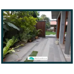 A well-designed walkway guides you through your garden and connects different spaces. This path uses large, modern stone pavers interspersed with small strips of grass, creating a clean and elegant transition from the house to the garden area.