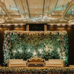 A stunning reception stage where a wall of delicate gypsophila creates a cloud-like effect. The design is framed with pastel florals and features elegant seating for a sophisticated look.