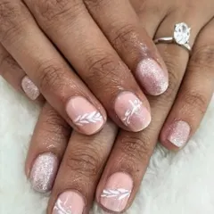 If you don't want extensions, a gel polish manicure on your natural nails is a great option. This client chose a shimmery nude base with delicate white leaf art.