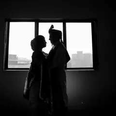 A powerful black and white silhouette of a bride and groom against a window. This classic technique creates a timeless and romantic image, focusing on their outlines and connection.