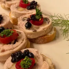 A close-up of our chicken and mushroom roulade canapés. These intricate bites are served on a toasted bread base and garnished with cherry tomato and caviar for a touch of elegance.