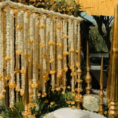 This is another angle of the elegant Haldi ritual space, showing the intricate details of the hanging floral backdrop and the traditional golden decor elements that add a touch of royalty.