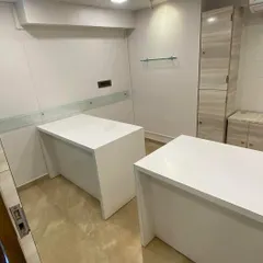 Here are the custom-designed workstations with a clean, white finish and integrated storage. The design includes practical features like a frosted glass panel for a touch of privacy and easy-to-access power outlets, all part of a complete office interior solution.
