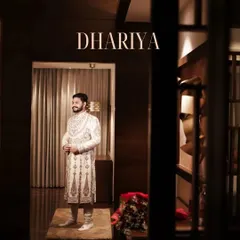 A full-length portrait of the groom, looking sharp and ready. The dark, moody lighting of the corridor adds a cinematic and sophisticated feel.