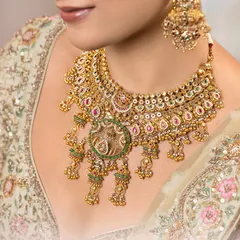 A closer look at the heart of our bridal collection. This exclusive choker, crafted in 22kt gold, showcases a fine Kundan setting, intricate meenakari detailing, and our signature jhumki drops, designed to frame your face with serene radiance.
