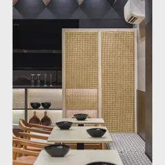 The minimalist side of the Japanese restaurant, featuring clean lines, natural textures like rattan screens, and a monochromatic color scheme that creates a calm and orderly dining space.
