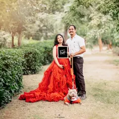 A joyful outdoor maternity shoot in a sunlit park, featuring an expecting couple with their beloved pet. We welcome all family members, furry ones included, to be part of your special session.