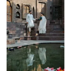 A classic pre-wedding pose of a couple descending the steps of a traditional stepwell. The reflection in the water adds a layer of depth and artistry to this heritage-themed portrait.