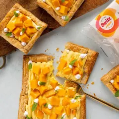 A flat-lay of mango puff pastries for Switz. This style of food photography is great for website banners and social media, showing the product in a bright, clean, and appetizing context.