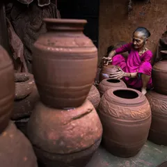 An elderly woman, a master of her craft, gives final shape to a large earthen pot. This portrait highlights the generations of skill and tradition passed down among the potters of Dharavi.