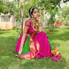 A beautiful portrait of a South Indian bride in a vibrant Kanjeevaram half saree. The makeup is kept fresh and minimal to complement the bright colors and traditional gold jewellery.