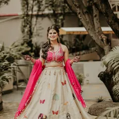The bride radiates joy in her colorful Haldi outfit. Her bright pink and cream lehenga with whimsical embroidery perfectly complements the festive and sunny atmosphere of the day.