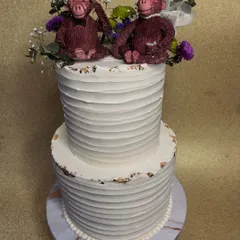 Our clients have the best ideas! This two-tiered wedding cake with a textured buttercream finish is topped with the most charming, custom-made monkey bride and groom toppers. It's proof that wedding cakes can be both elegant and playful.