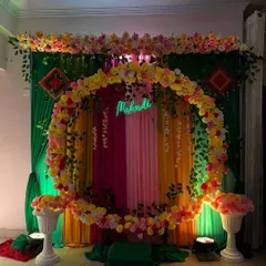 For a fun and colorful Mehndi night, I designed this circular floral arch with a custom 'Mehndi' neon sign. The backdrop uses a mix of green, yellow, and pink drapes, creating a vibrant and Instagram-worthy photo corner for the bride and guests.