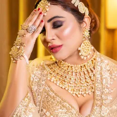 A powerful shot of celebrity Arshi Khan showcasing a dramatic smoky eye and perfectly contoured features. This close-up highlights the rich pigmentation of the makeup and the intricate design of the heavy gold jewellery set.