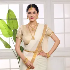 This full-length shot showcases a model in a traditional South Indian bridal look, featuring a temple jewellery set with a waist belt (kamarbandh) and maang tikka. The styling with a classic white and gold saree is ideal for heritage brand campaigns.