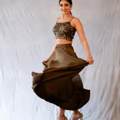 A full-length studio shot capturing a moment of happy movement. The flowing skirt and bright smile create a fun and energetic portrait, perfect for fashion or lifestyle photography.