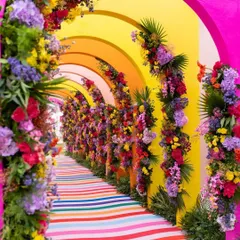 A spectacular rainbow tunnel entrance for a vibrant daytime event, using colorful floral arrangements on repeating arches to create an immersive and joyful welcome for guests.